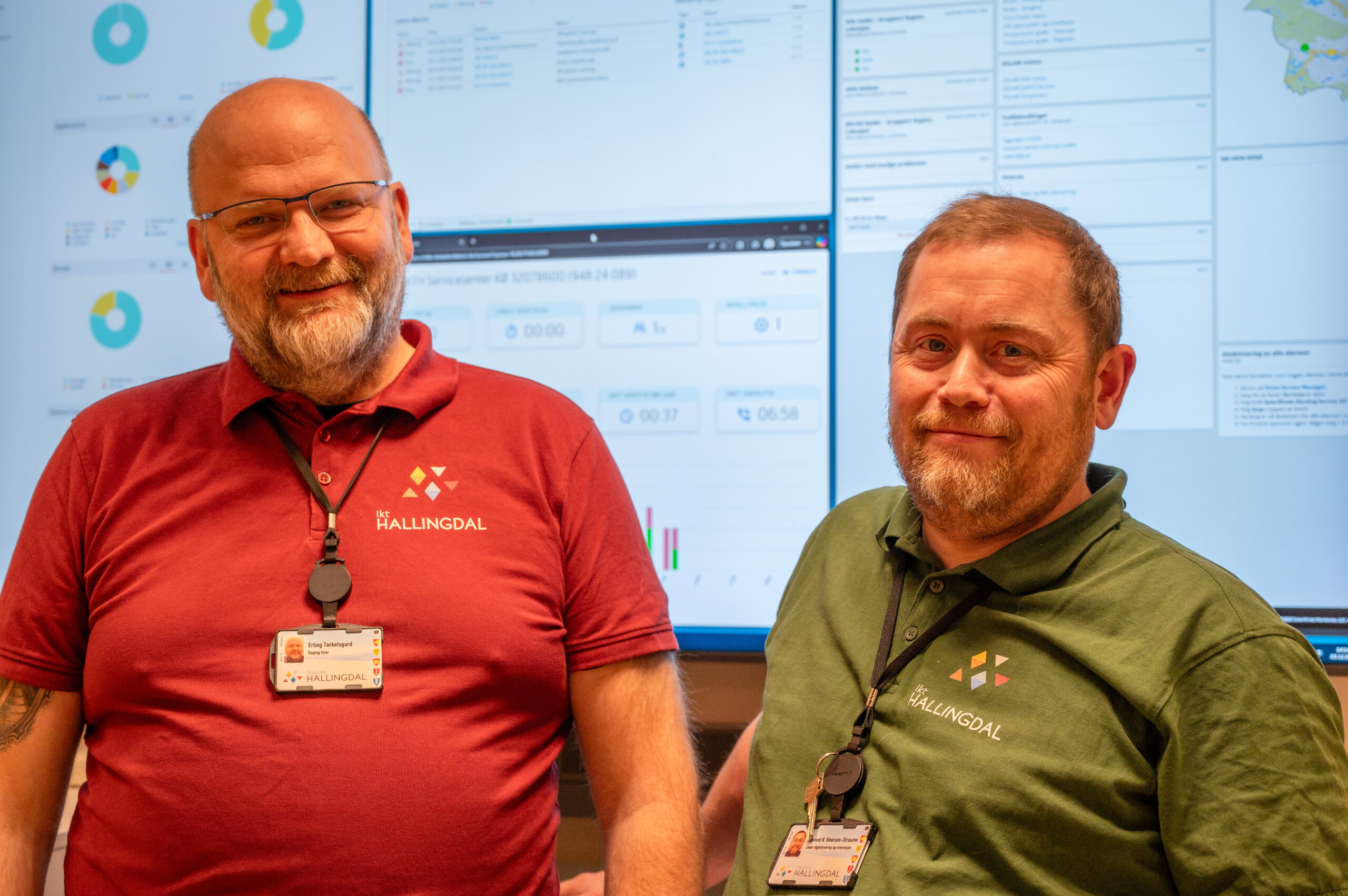 Erling Torkelsgard og Øyvind K. Vinorum-Straume i Hallingdal IKT står foran en statustavle i IKT Hallingdal sine kontorer på Gol.